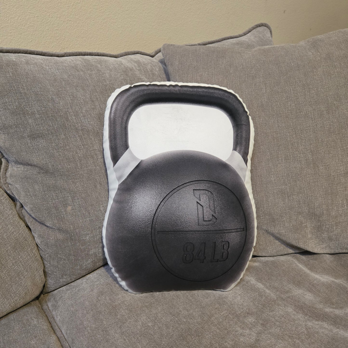 Kettlebell-inspired Kettle Nap Pillow resting on couch for post-workout relaxation